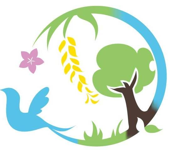 興田地区振興会のロゴ（青い鳥、緑の木、黄色い稲穂、ピンクの花）